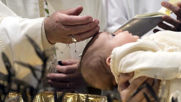 Ein Priester tauft ein Baby mit Wasser.