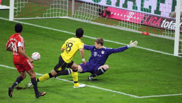 Ein Fußballspieler schießt auf das Tor, während der Torwart versucht, den Ball abzuwehren.