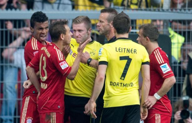Fußballspieler von Bayern München und Borussia Dortmund diskutieren mit dem Schiedsrichter.