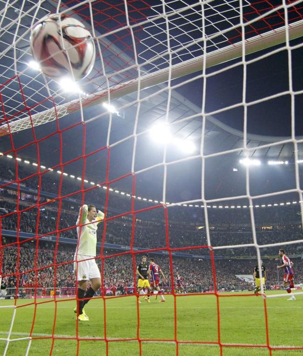 Ein Fußball fliegt in das Netz, während ein Torwart die Hände über dem Kopf zusammenschlägt.