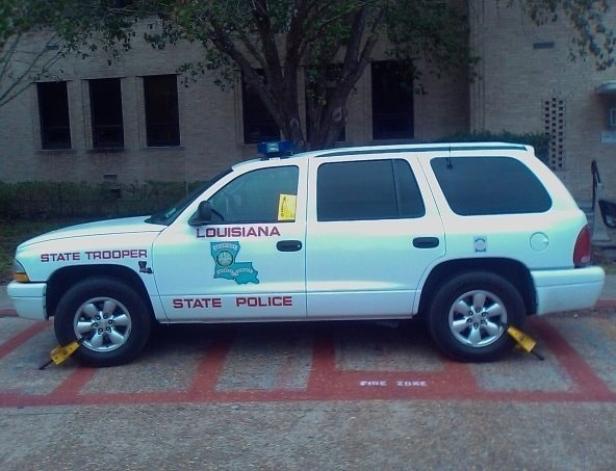 Ein weißer Louisiana State Trooper SUV mit Radklemmen steht in einer Feuerwehrzone.
