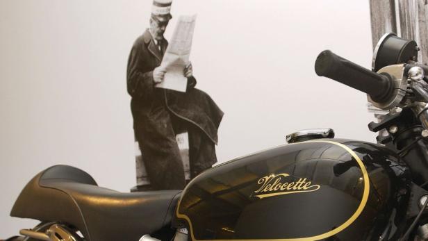 Eine Velocette-Maschine vor dem Hintergrund eines Mannes, der Zeitung liest.