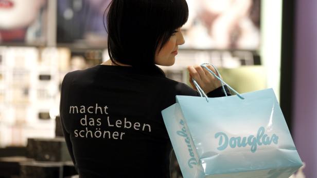 Eine Frau mit einer Douglas-Einkaufstasche über der Schulter.