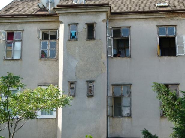 Die Fassade eines alten Gebäudes mit mehreren geöffneten Fenstern.