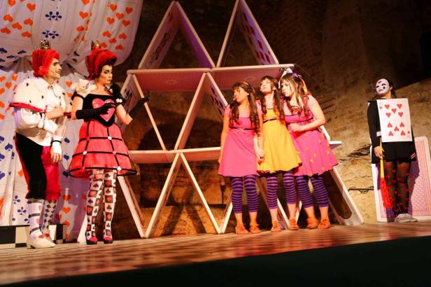 Eine Aufführung von „Alice im Wunderland“ mit der Herzkönigin und anderen Figuren auf der Bühne.