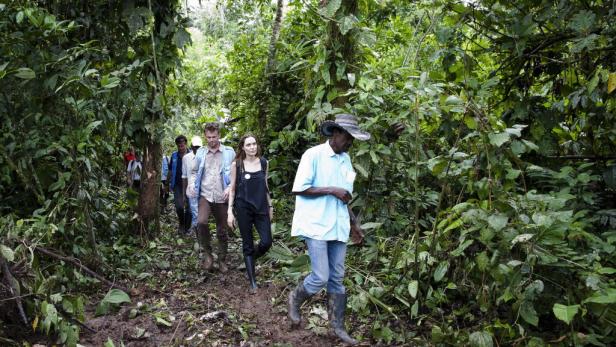 Angelina Jolie wandert mit einer Gruppe von Menschen durch einen dichten Dschungel.