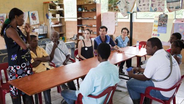 Angelina Jolie sitzt mit anderen Personen an einem Tisch in einem Raum.