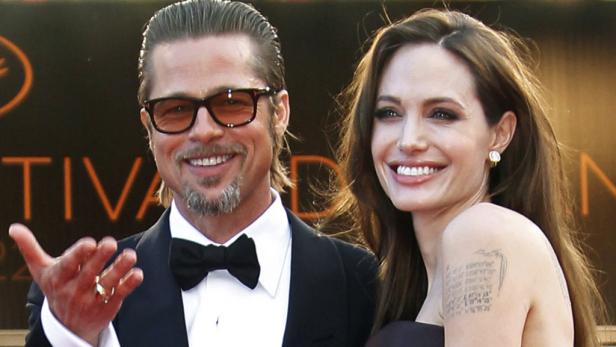 Brad Pitt und Angelina Jolie lächeln auf einem roten Teppich.