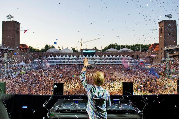 Ein DJ steht vor einer jubelnden Menschenmenge auf dem Summerburst Festival.