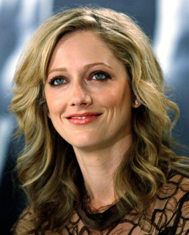 Judy Greer lächelt in einem braunen Spitzenoberteil.