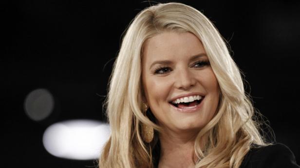 Jessica Simpson lächelt mit blonden Haaren und Ohrringen.