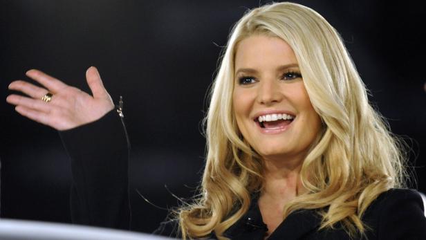 Jessica Simpson lächelt und hebt ihre Hand.