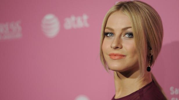 Julianne Hough posiert vor einem rosafarbenen Hintergrund.
