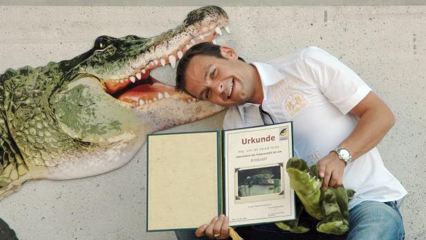 Ein Mann hält eine Urkunde für die Patenschaft eines Krokodils und ein Plüschkrokodil in der Hand.