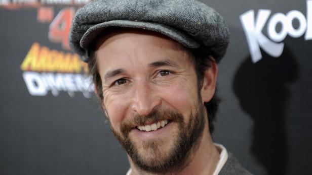 Schauspieler Josh Peck mit Bart und Schiebermütze lächelt.