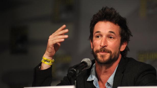 Noah Wyle spricht auf einer Veranstaltung in ein Mikrofon.