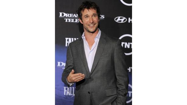 Noah Wyle posiert auf einem Event in einem grauen Anzug.