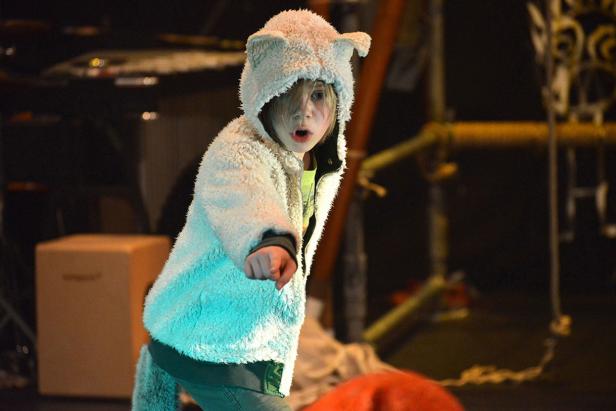 Ein Kind mit einem Tierkostüm mit Ohren und Schwanz blickt überrascht in die Kamera.