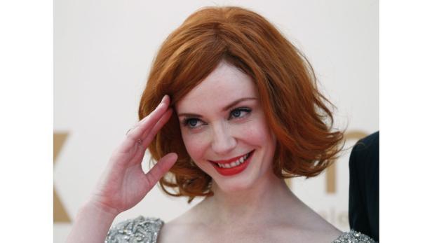 Christina Hendricks lächelt und hält ihre Hand an die Stirn.