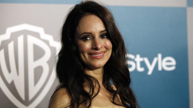 Shannon Elizabeth lächelt vor einem Hintergrund mit dem Warner Bros. Logo.