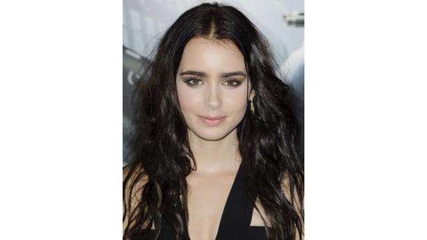 Ein Porträt von Lily Collins mit dunklen, gewellten Haaren und einem schwarzen Kleid.