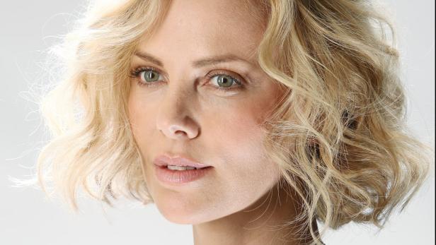 Porträt von Charlize Theron mit blonden, gewellten Haaren.