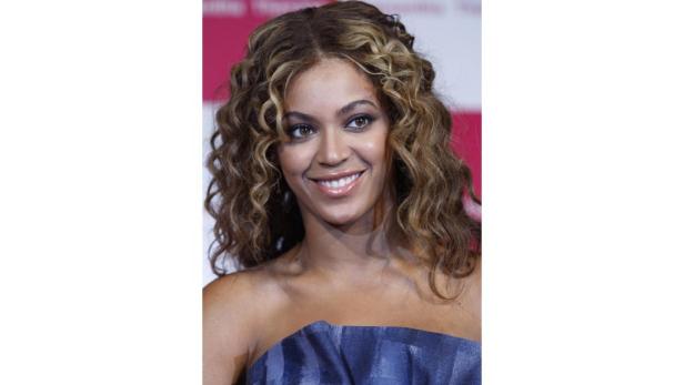 Porträt von Beyoncé mit lockigem, blond gesträhntem Haar und einem blauen Kleid.