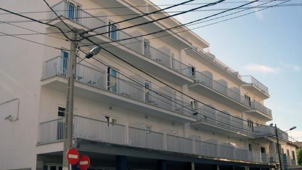 Ein weißes Gebäude mit mehreren Balkonen unter einem blauen Himmel.