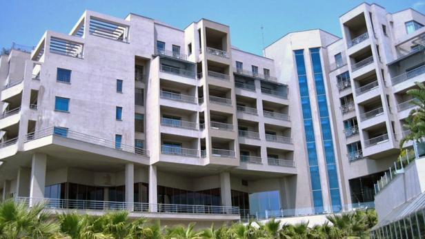 Ein großes, modernes Hotelgebäude mit mehreren Balkonen und blauen Fenstern.