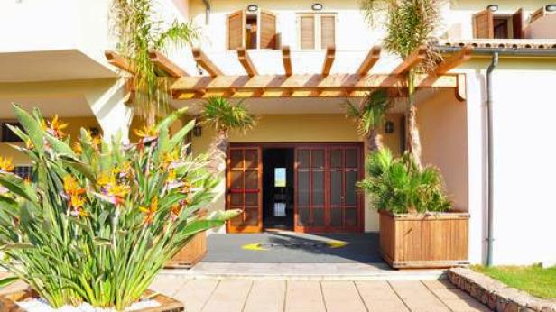 Der Eingang eines Gebäudes ist mit tropischen Pflanzen geschmückt.
