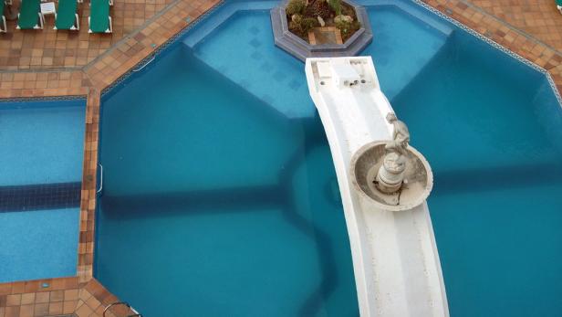 Ein Schwimmbad mit Wasserrutsche und einer Statue als Dekoration.