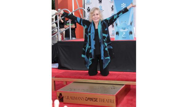 Tippi Hedren kniet vor ihrem Hand- und Fußabdruck am Grauman's Chinese Theatre.