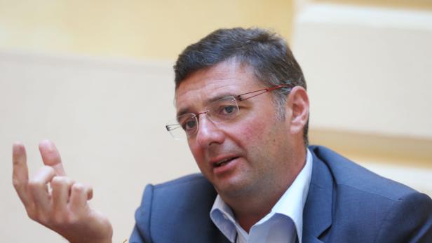 Ein Mann mit Brille gestikuliert während eines Gesprächs.