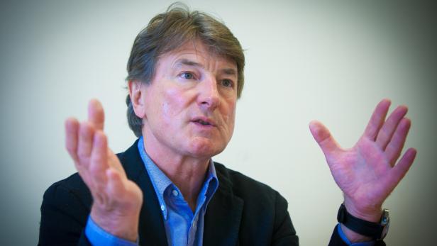 Ein Mann mit braunen Haaren gestikuliert mit beiden Händen.