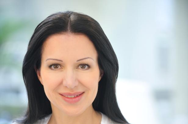 Porträt einer lächelnden Frau mit dunklen, langen Haaren.