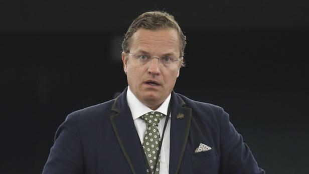 Ein Mann mit Brille und Anzug blickt in die Kamera.