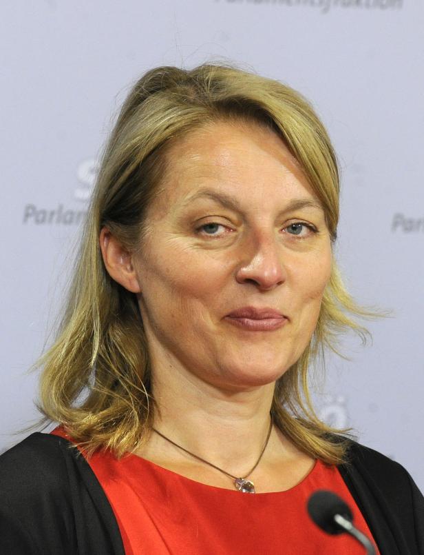 Eine Frau mit blonden Haaren und einem roten Oberteil schaut in die Kamera.