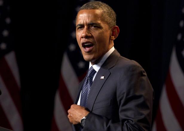 Barack Obama hält eine Rede vor amerikanischen Flaggen.