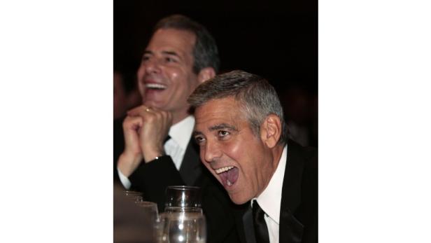 George Clooney und ein weiterer Mann lachen bei einer Veranstaltung.
