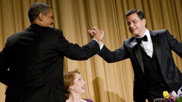Barack Obama und Jimmy Kimmel geben sich vor einem goldenen Vorhang die Hand.