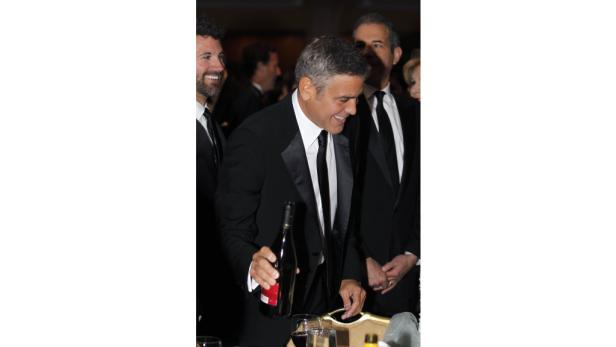 George Clooney gießt Wein in ein Glas.
