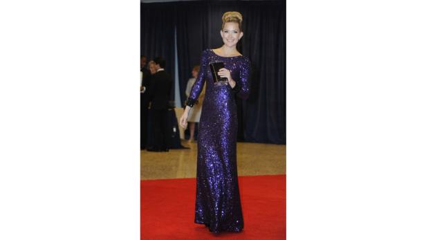 Kate Hudson in einem langen, violetten Paillettenkleid auf einem roten Teppich.