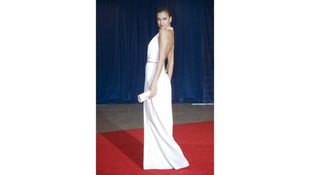 Irina Shayk in einem weißen Kleid auf einem roten Teppich.