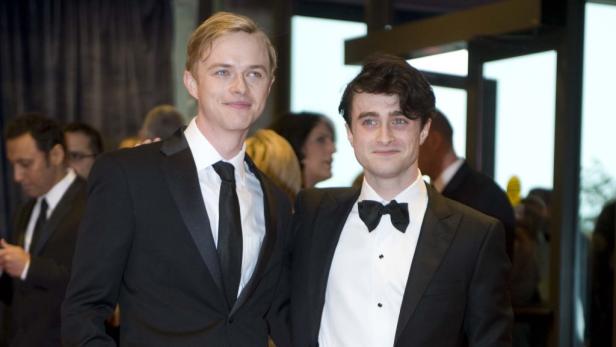 Daniel Radcliffe posiert mit einem Mann im Anzug auf einem Event.