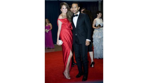 Chrissy Teigen und John Legend posieren auf einem roten Teppich.