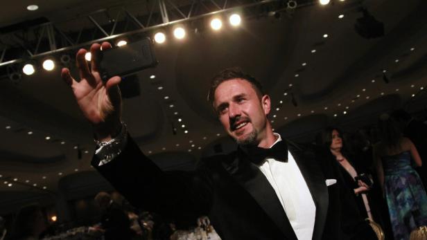 Ein Mann im Smoking macht ein Selfie mit seinem Smartphone.