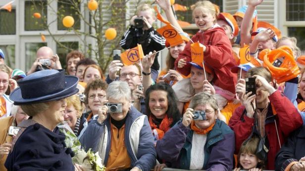 Königin Beatrix wird von einer jubelnden Menge mit orangefarbenen Accessoires fotografiert.