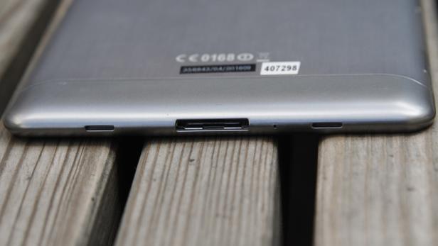 Die Unterseite eines Tablets mit verschiedenen Anschlüssen liegt auf einer Holzoberfläche.