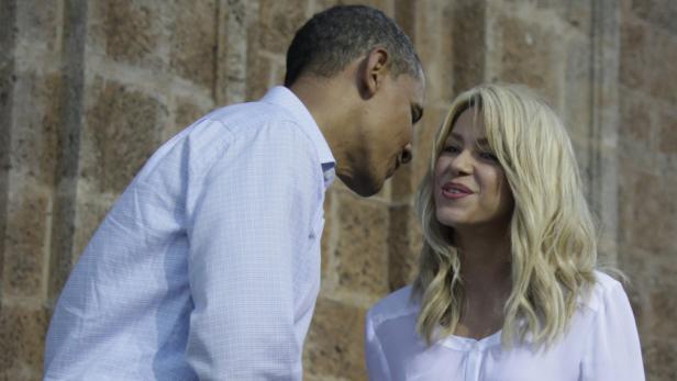 Barack Obama und Shakira unterhalten sich vor einer Steinwand.