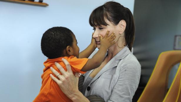 Eine Frau hält ein Kind im Arm, das ihre Wangen berührt.